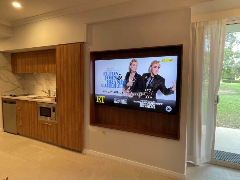 large tv mounted in recess next to kitchen counter
