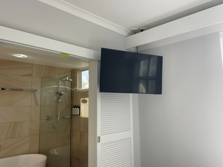 tv mounted high on wall in bathroom of holiday apartment in the swan valley
