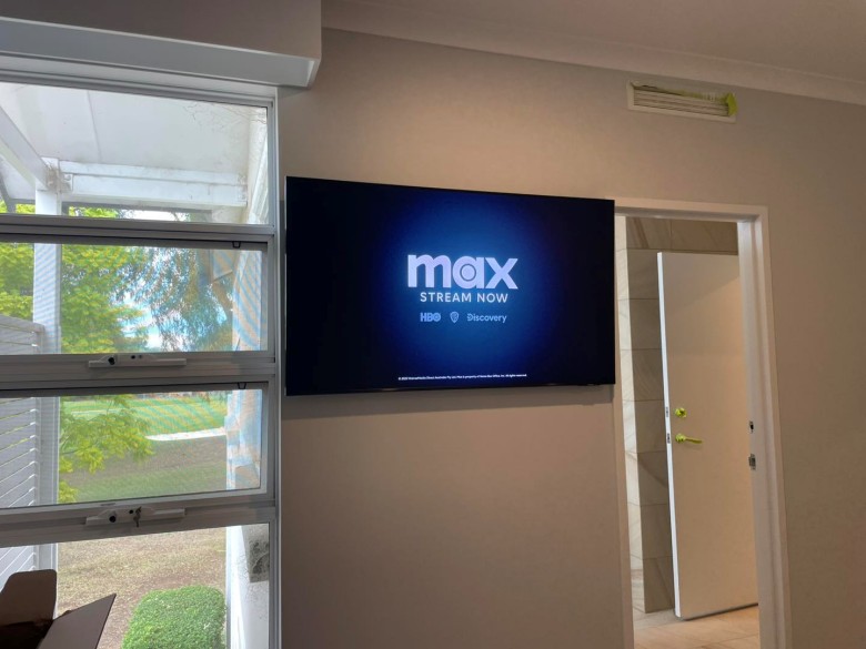 tv hanging on wall between window and internal door.