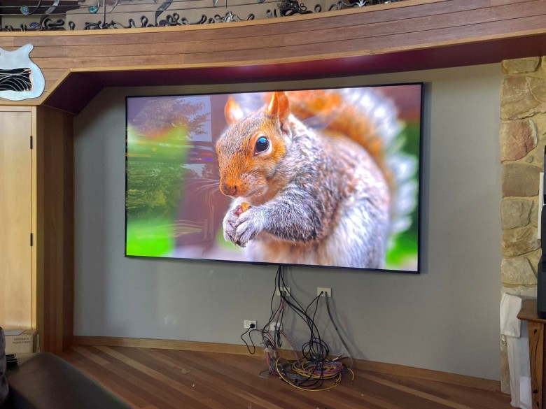 large TV mounted on the wall with cables still showing